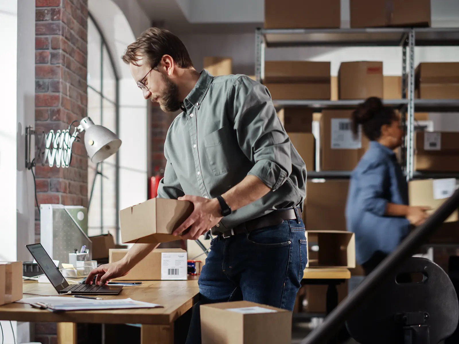 Ondernemer verwerkt bestellingen in eigen magazijn en voert ordergegevens in op laptop – praktijkervaring in e-commerce.